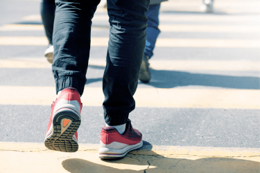 Someone in red shoes walking at a crosswalk