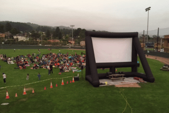 Movie screen on Arcata Ball Park field with crowd watching